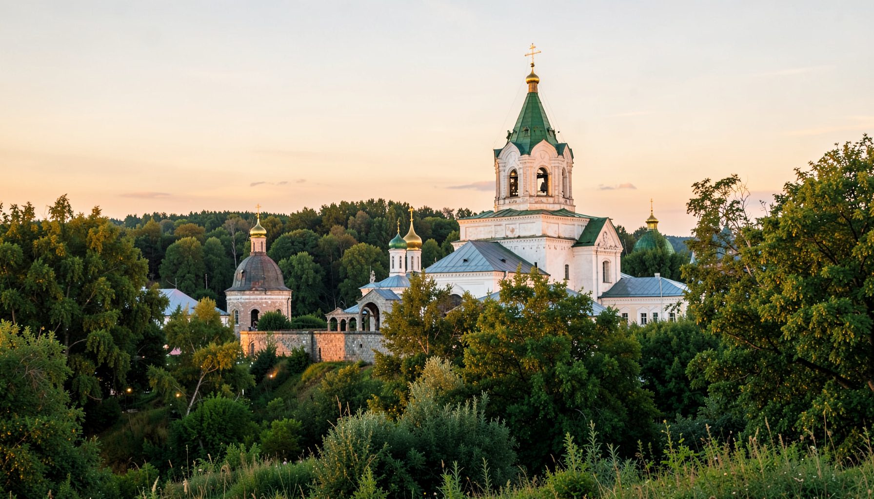 Вид на монастырский комплекс с храмом святого Онуфрия, окружённый зеленью, в тёплом вечернем свете